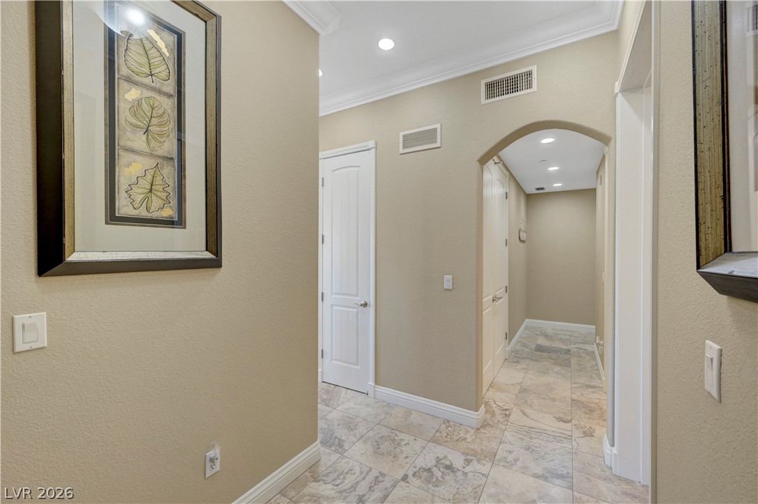 10 Strada Bella Vista, Unit 101 Henderson, NV 89011 - Photo 6 of 64 Corridor featuring arched entry, crown molding, recessed lighting, and a textured wall
