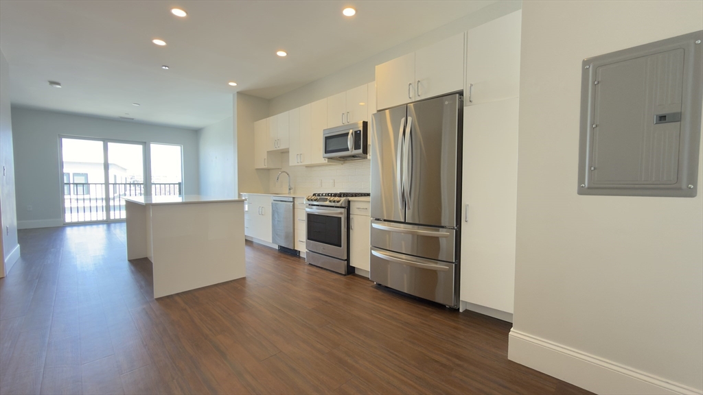 a kitchen with stainless steel appliances wooden floor and large window