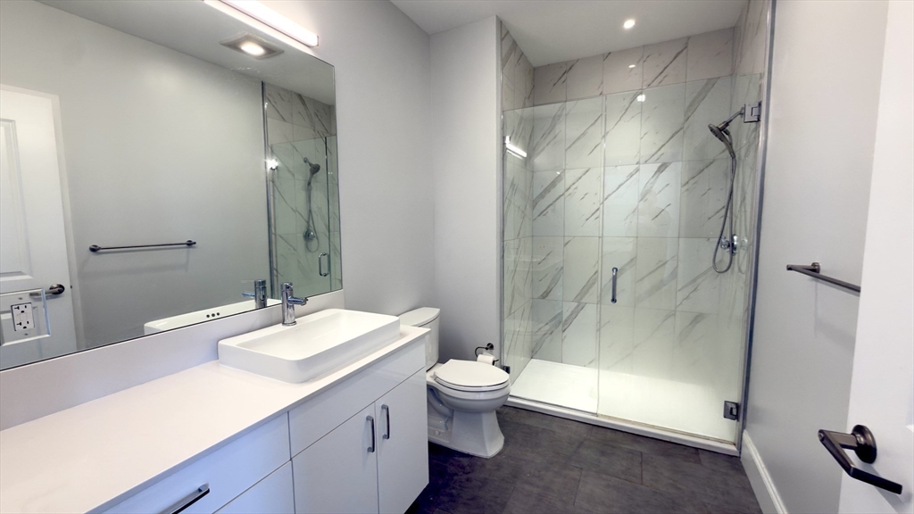 205 Maverick Street, Unit 412 Boston, MA 02128 - Photo 14 of 15 a bathroom with a double vanity sink toilet and shower