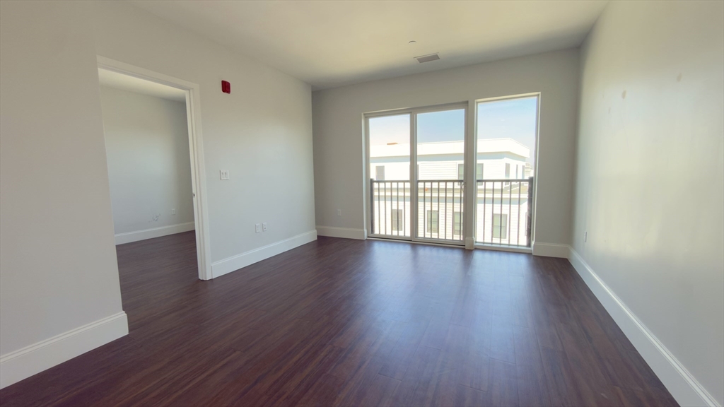 205 Maverick Street, Unit 412 Boston, MA 02128 - Photo 5 of 15 a view of an empty room with wooden floor and a window