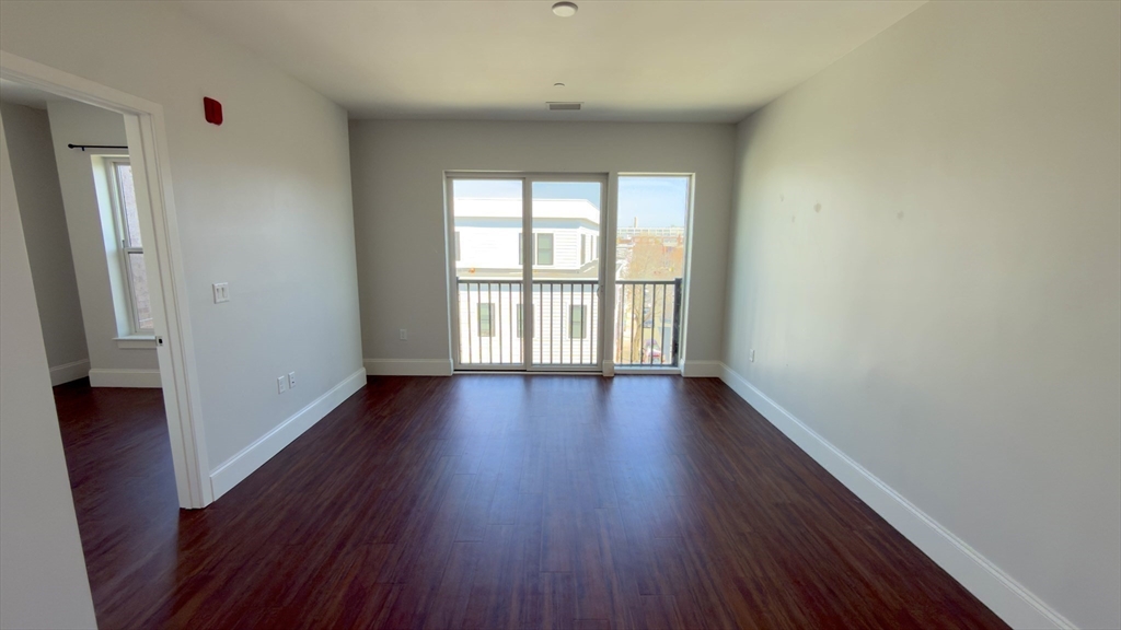 205 Maverick Street, Unit 412 Boston, MA 02128 - Photo 7 of 15 a view of an empty room with wooden floor and a window