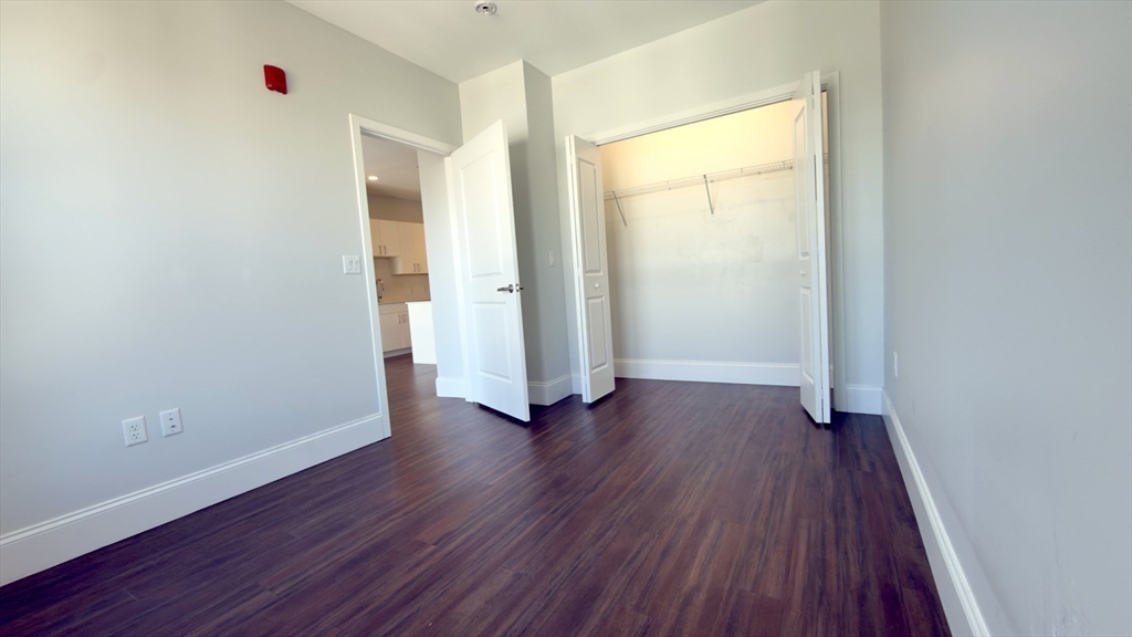 205 Maverick Street, Unit 412 Boston, MA 02128 - Photo 8 of 15 an empty room with wooden floor and windows