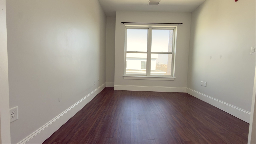 205 Maverick Street, Unit 412 Boston, MA 02128 - Photo 10 of 15 an empty room with wooden floor and windows