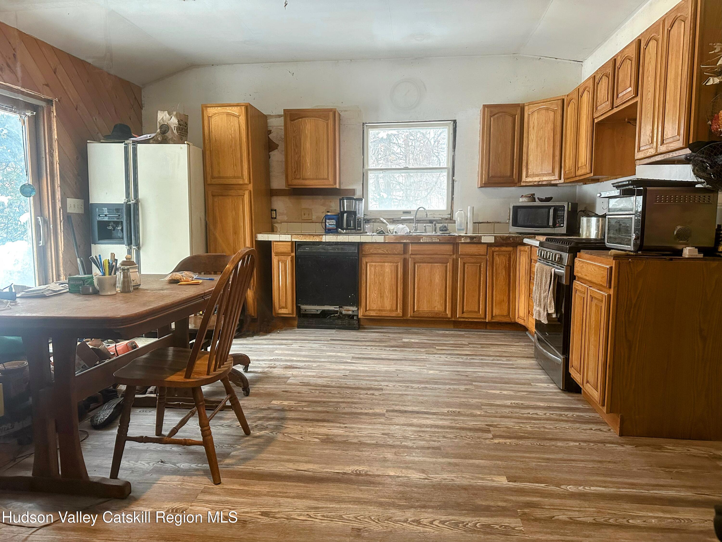 16 Field Road Greenville, NY 12083 - Photo 3 of 22 a kitchen with stainless steel appliances kitchen island granite countertop a refrigerator a stove a sink dishwasher and wooden cabinets with wooden floor