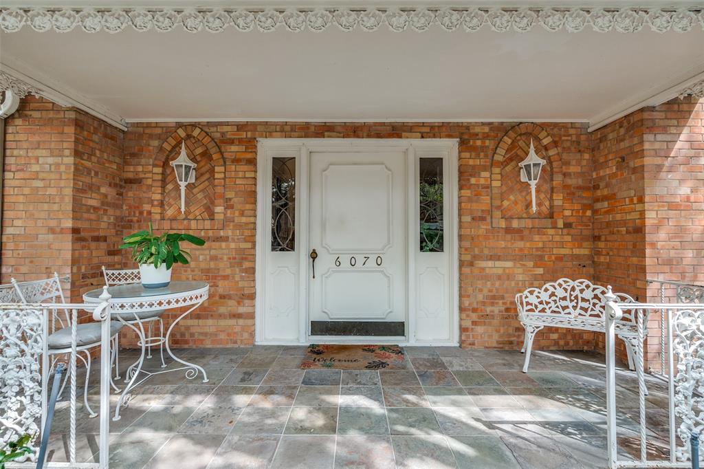 6070 Averill Way, Unit A Dallas, TX 75225 - Photo 23 of 26 The property gated front area features a brick exterior, a white front door with sidelights, and a charming patio overlooking the pool.
