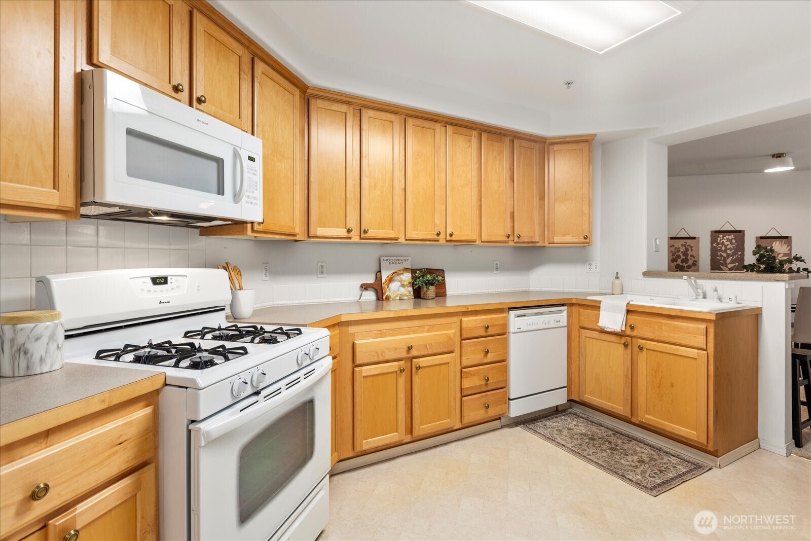 8500 Main Street, Unit F205 Edmonds, WA 98026 - Photo 11 of 30 a kitchen with stainless steel appliances granite countertop a stove a sink and a microwave