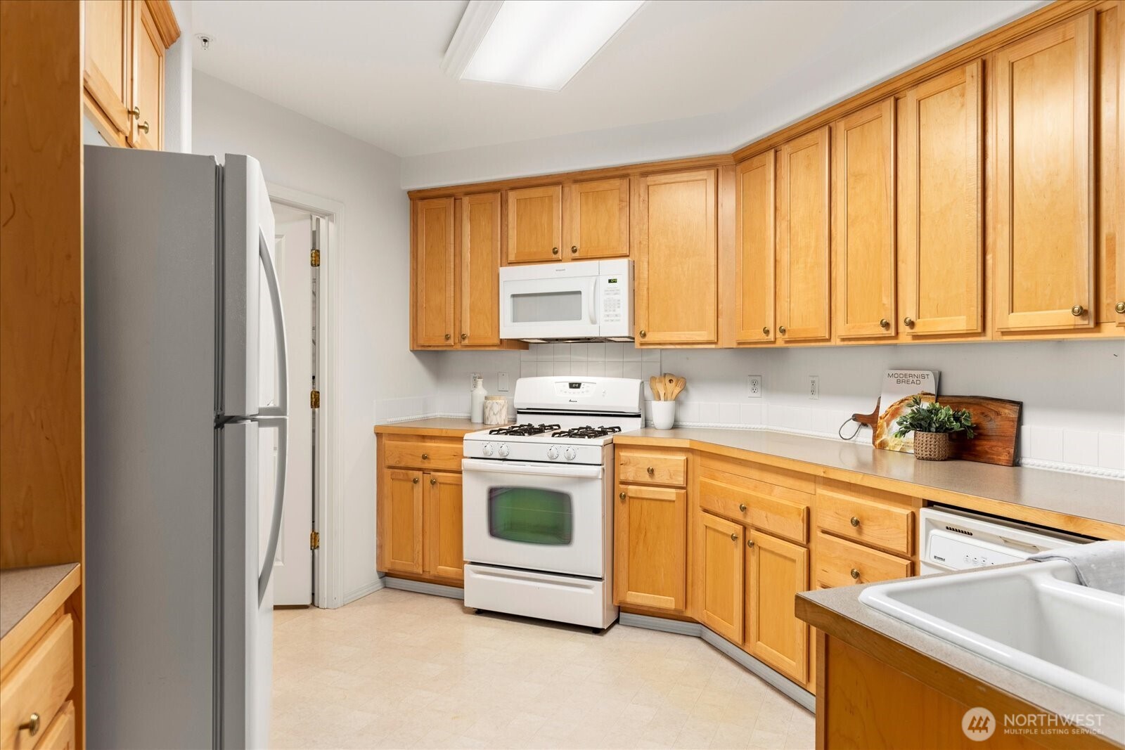 8500 Main Street, Unit F205 Edmonds, WA 98026 - Photo 10 of 30 a kitchen with a stove a sink and a refrigerator