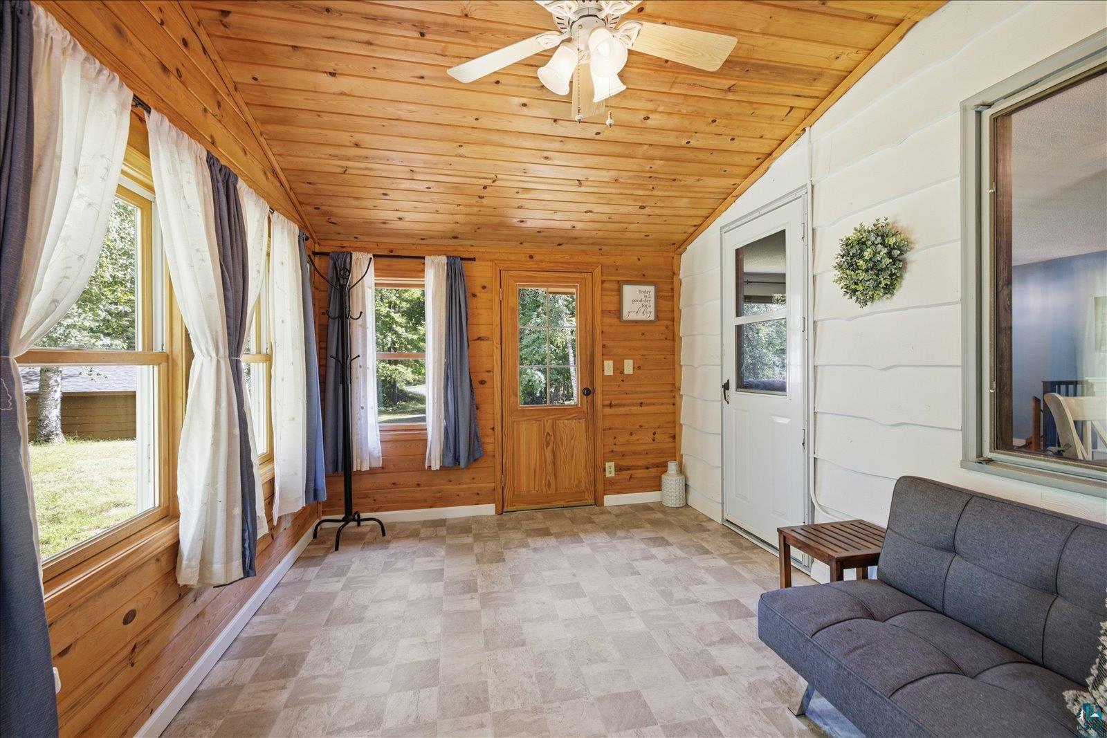 6377 Bergstrom Road Saginaw, MN 55779 - Photo 19 of 20 Sunroom featuring wood-paneled walls and ceiling, multiple windows, a ceiling fan, and checkered tile flooring