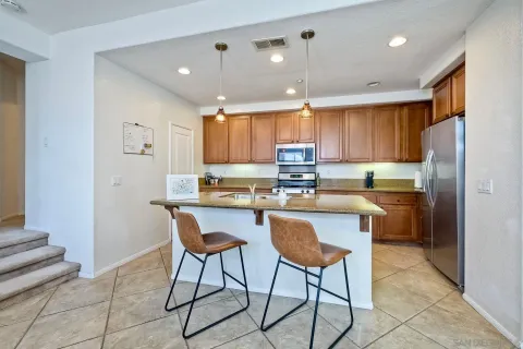 a kitchen with kitchen island granite countertop wooden cabinets and a refrigerator