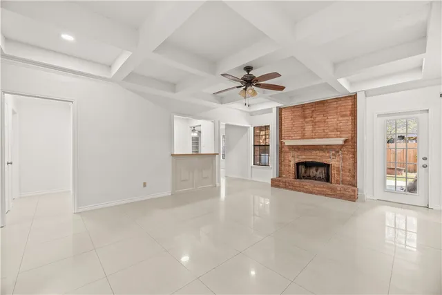 an empty room with windows fireplace and fans