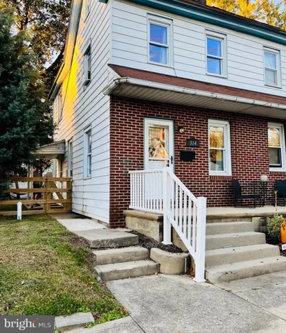 a view of a house with a small yard and large tree and wooden fence