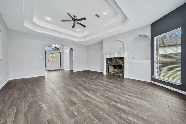 a view of an empty room with wooden floor fireplace and a window