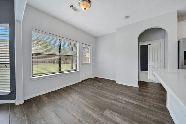 an empty room with wooden floor and windows