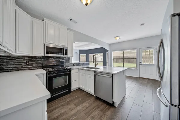 a kitchen with stainless steel appliances granite countertop a stove a sink and a refrigerator