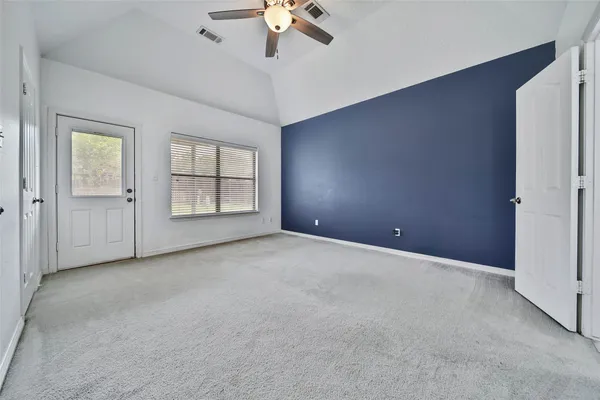 an empty room with chandelier fan and windows