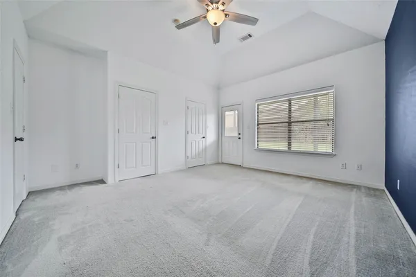 an empty room with chandelier fan and windows