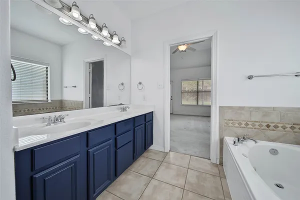 a spacious bathroom with a tub sink and mirror