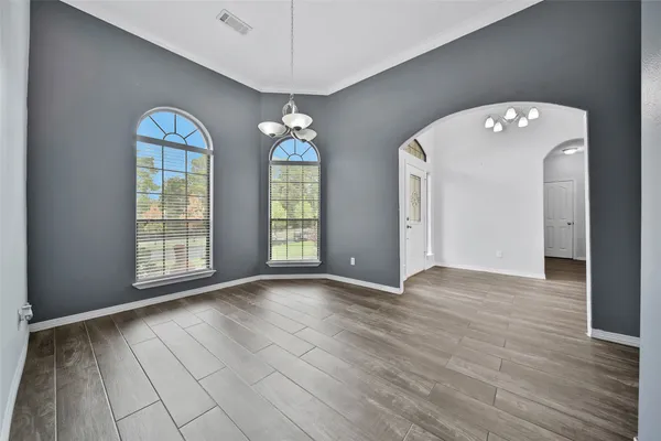 a view of an empty room with window and wooden floor