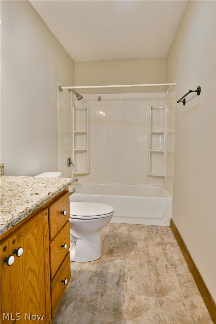754 Warner Road Hubbard, OH 44425 - Photo 23 of 46 Bathroom featuring a full tub and shower combination with integrated shelving, a white toilet, and wood-finish flooring
