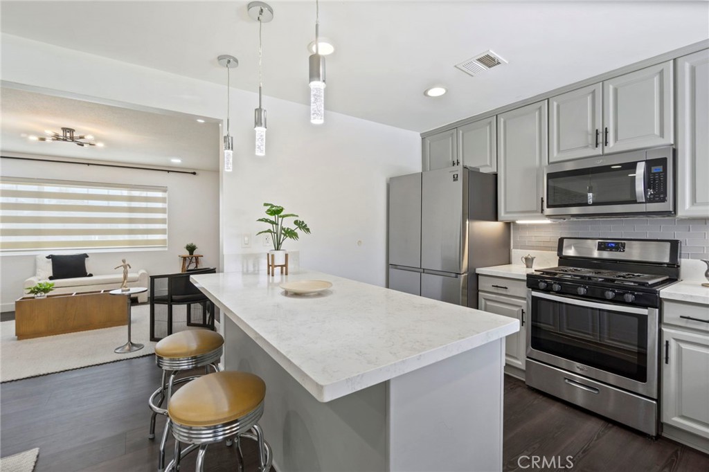 6212 Santa Rita Avenue Garden Grove, CA 92845 - Photo 13 of 50 a kitchen with stainless steel appliances kitchen island granite countertop a stove a refrigerator a kitchen island a table and chairs with wooden floor