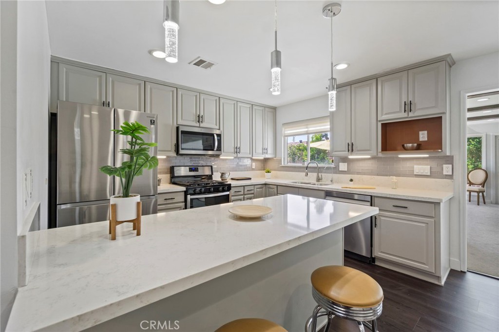 6212 Santa Rita Avenue Garden Grove, CA 92845 - Photo 14 of 50 a kitchen with granite countertop a stove sink microwave and refrigerator