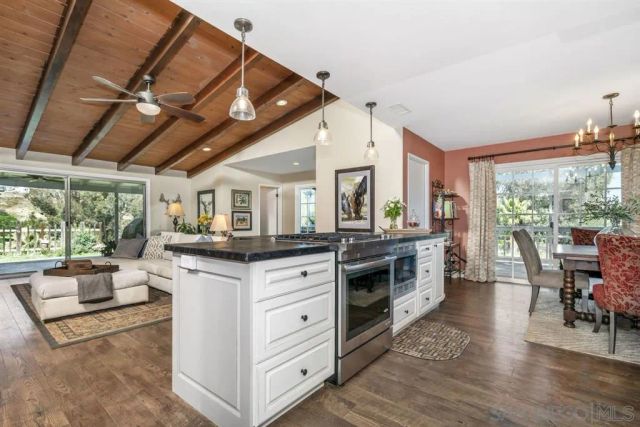 a kitchen with stainless steel appliances granite countertop a stove and a view of living room