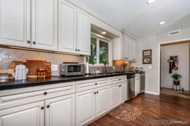a kitchen with granite countertop white cabinets and stainless steel appliances