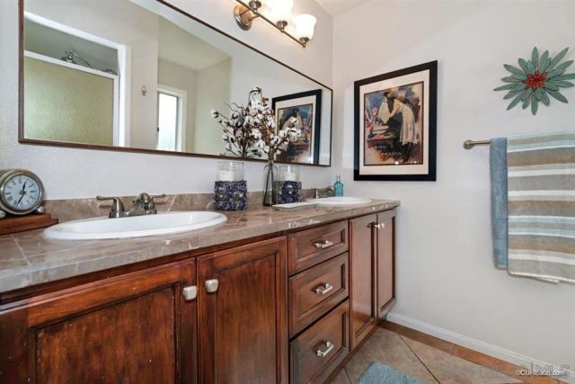 a bathroom with a granite countertop double vanity sink and a mirror