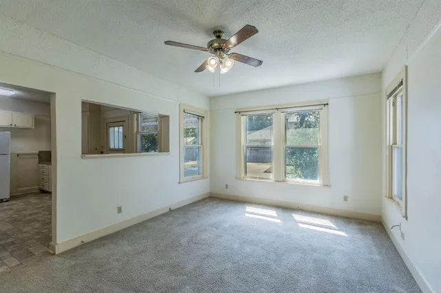an empty room with a ceiling fan and window