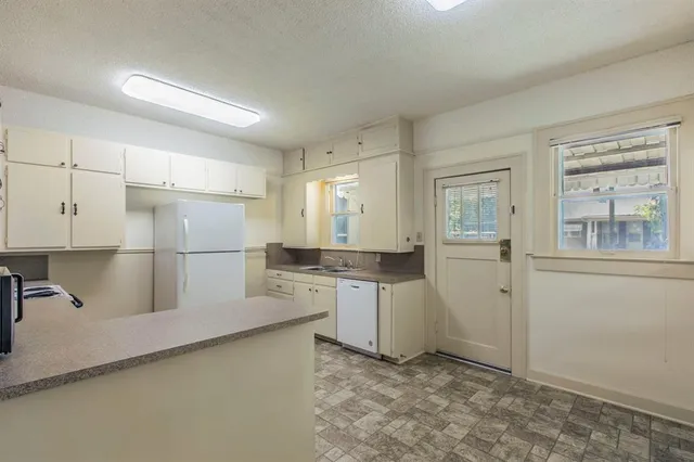 a kitchen with a refrigerator a stove top oven and white cabinets