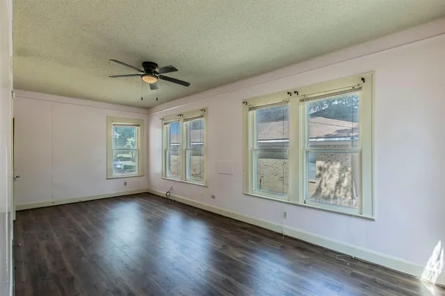 a view of an empty room with a window and wooden floor