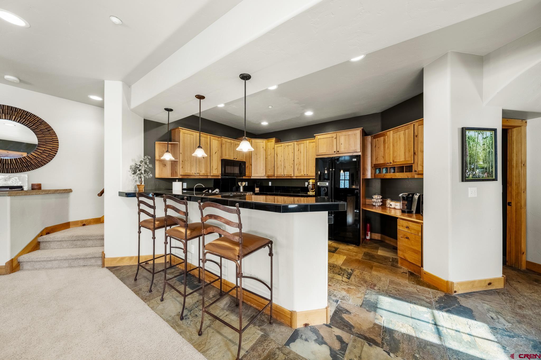 114 Limestone Court Durango, CO 81301 - Photo 7 of 35 a kitchen with stainless steel appliances kitchen island granite countertop a refrigerator a stove a sink a dining table and chairs with wooden floor