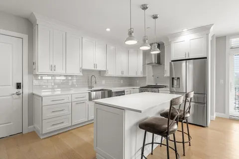 a kitchen with kitchen island a white cabinets and refrigerator