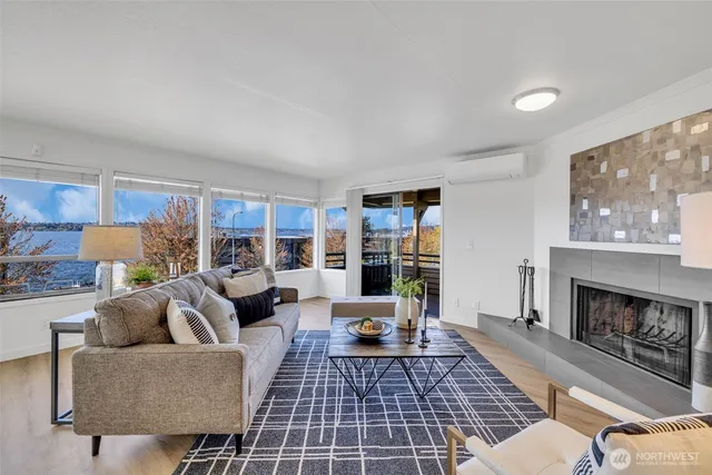 a living room with furniture a rug a fireplace and a large window
