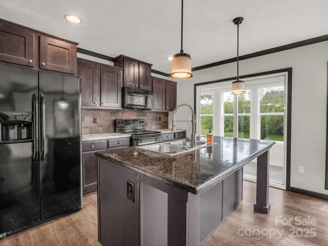 a kitchen with stainless steel appliances granite countertop a sink a refrigerator a stove and a center island