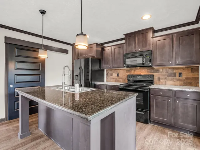 a kitchen with stainless steel appliances granite countertop a sink a stove and a refrigerator