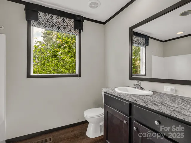 a bathroom with a granite countertop sink toilet and mirror