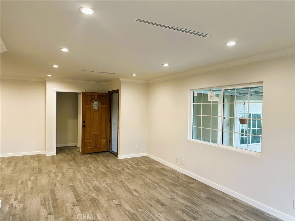 7307 Foothill Boulevard Tujunga, CA 91042 - Photo 6 of 27 a view of an empty room with wooden floor and a window