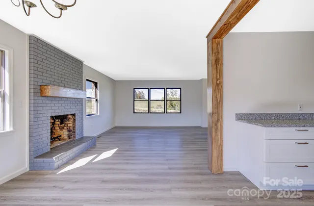 a view of an empty room with a window and fireplace