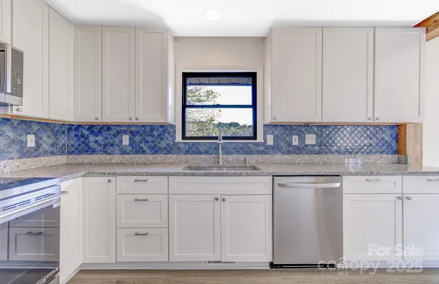 a kitchen with granite countertop white cabinets and sink
