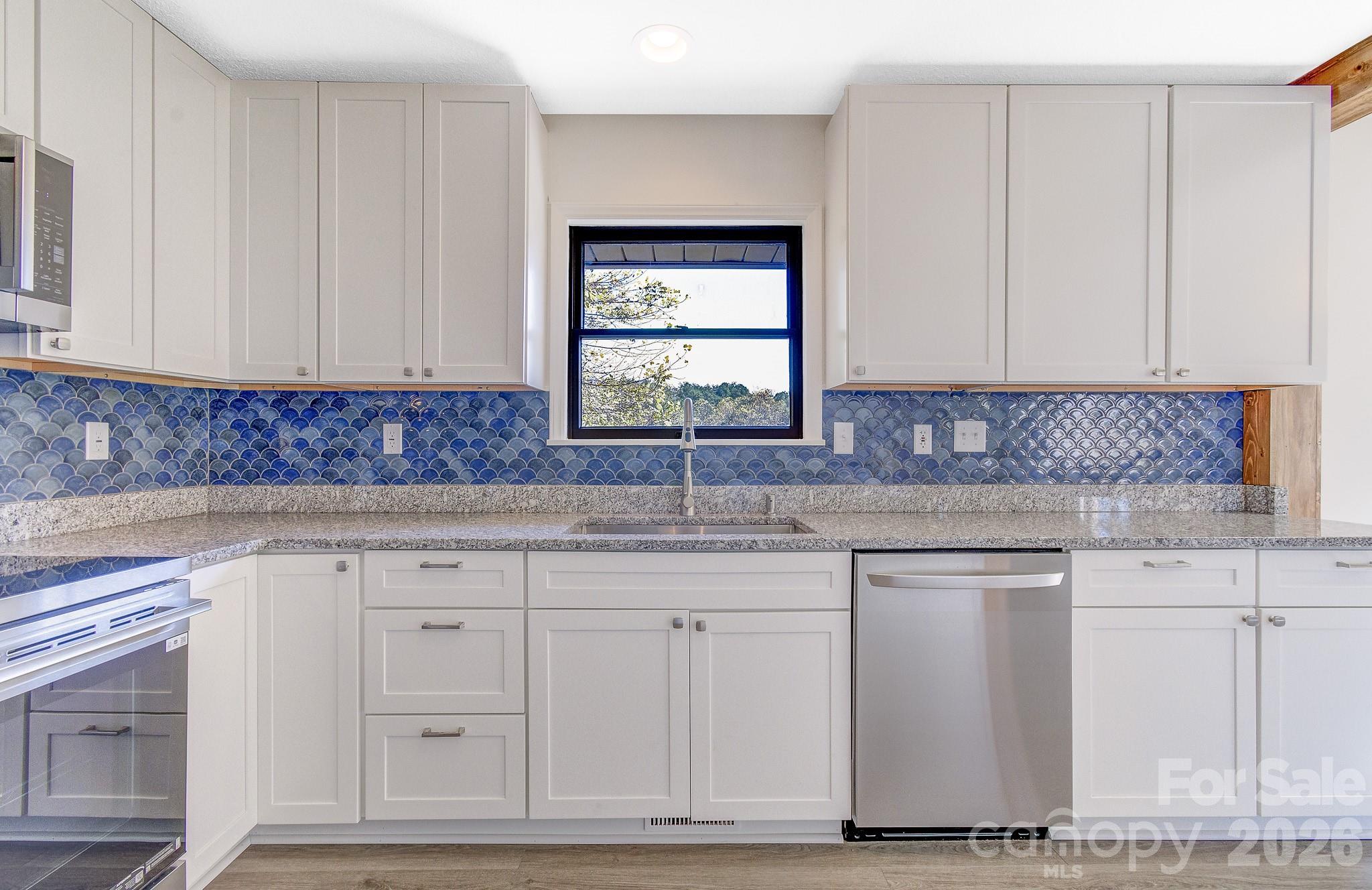1248 Jenkins Valley Road Alexander, NC 28701 - Photo 20 of 43 a kitchen with granite countertop white cabinets and sink