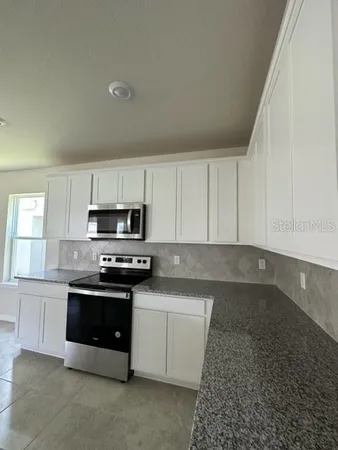 a kitchen with stainless steel appliances granite countertop a stove a sink and a microwave