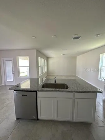 a kitchen with granite countertop a sink and white cabinets