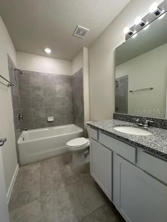 a bathroom with a granite countertop sink a toilet a bathtub and a shower