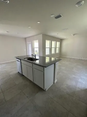 a kitchen with granite countertop a sink and white cabinets