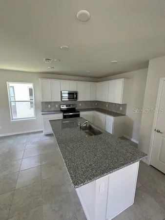 a kitchen with a sink a counter top space cabinets and stainless steel appliances