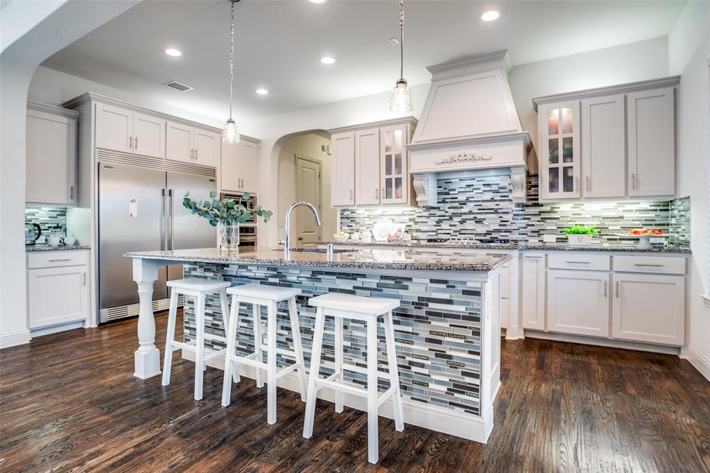 608 Arma Road Allen, TX 75002 - Photo 11 of 40 a kitchen with stainless steel appliances kitchen island granite countertop a wooden floor and white cabinets