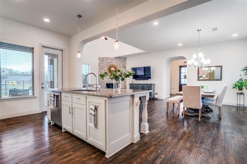608 Arma Road Allen, TX 75002 - Photo 37 of 40 a kitchen with stainless steel appliances granite countertop a stove top oven a sink dishwasher a dining table and chairs with wooden floor