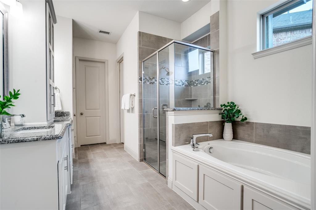 608 Arma Road Allen, TX 75002 - Photo 22 of 40 a bathroom with a tub a sink and mirror