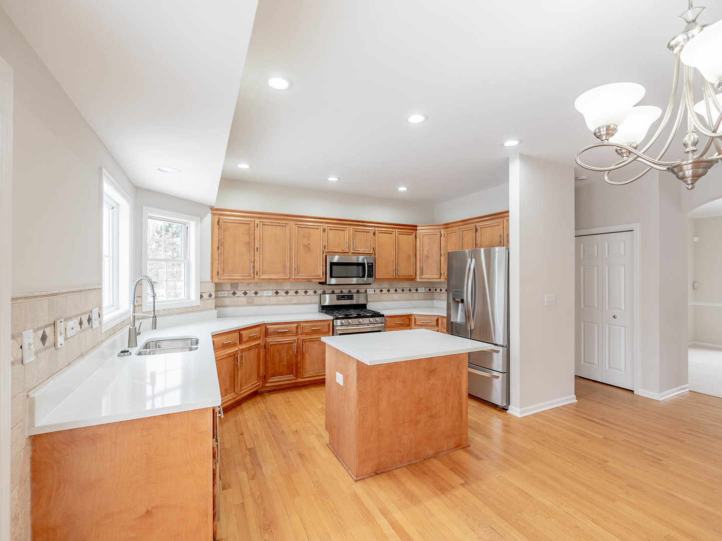975 Merbach Court Carol Stream, IL 60188 - Photo 8 of 28 a large kitchen with kitchen island a sink a stove a refrigerator and a dining table with wooden floor